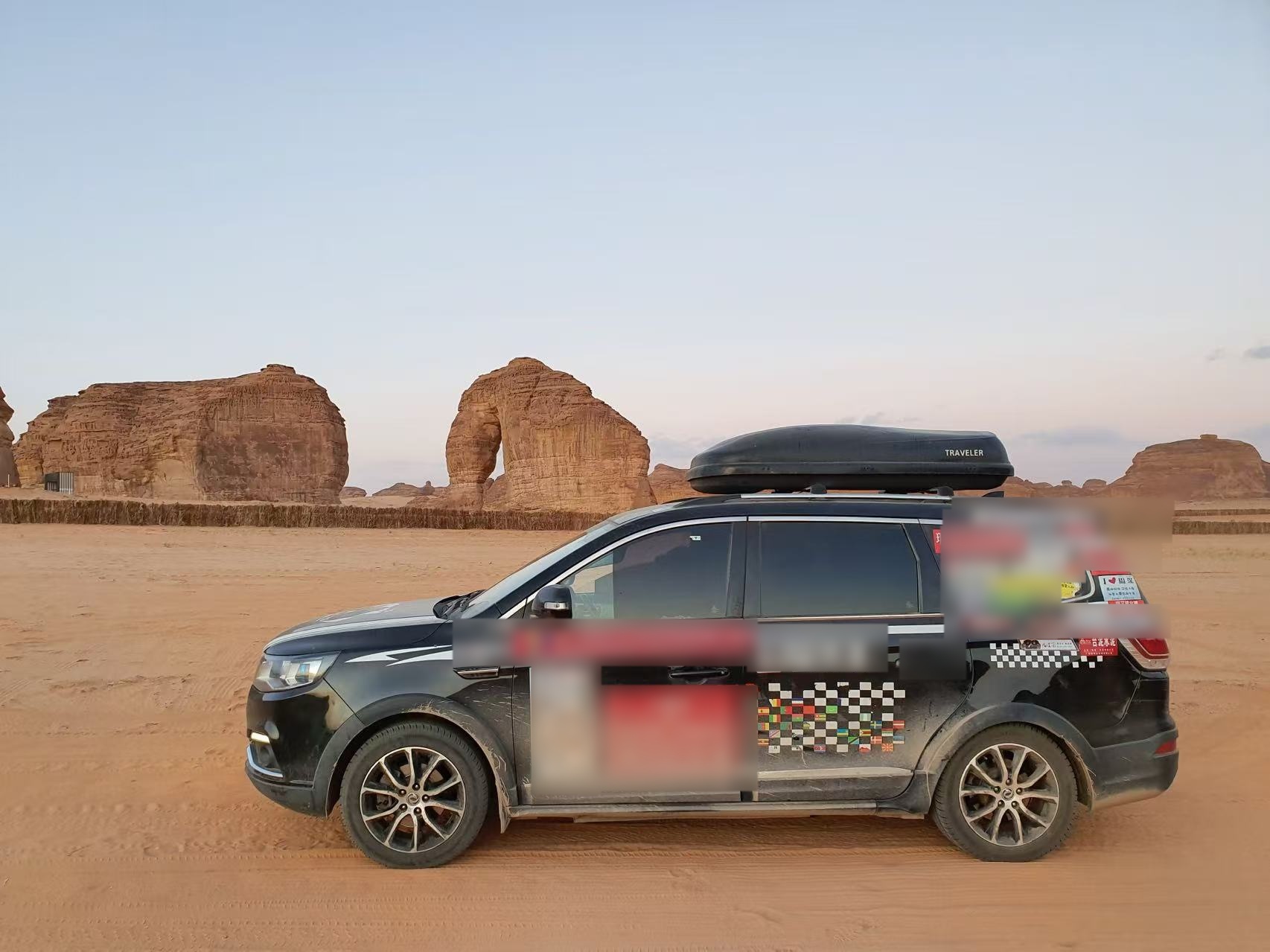 The travelling car with Janet's Zhou Shen sticker parked beside a rock arch.
