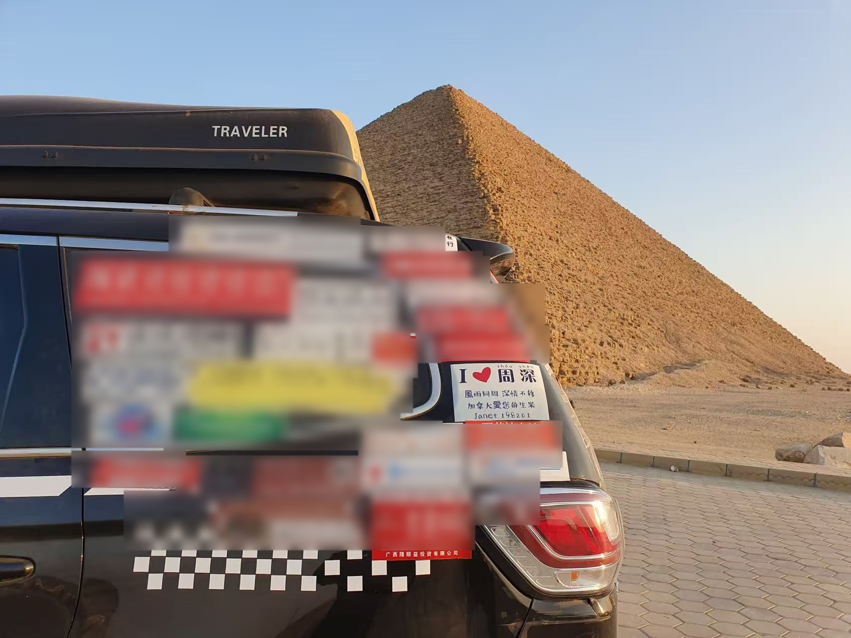 The travelling car with Janet's Zhou Shen sticker parked beside pyramids.