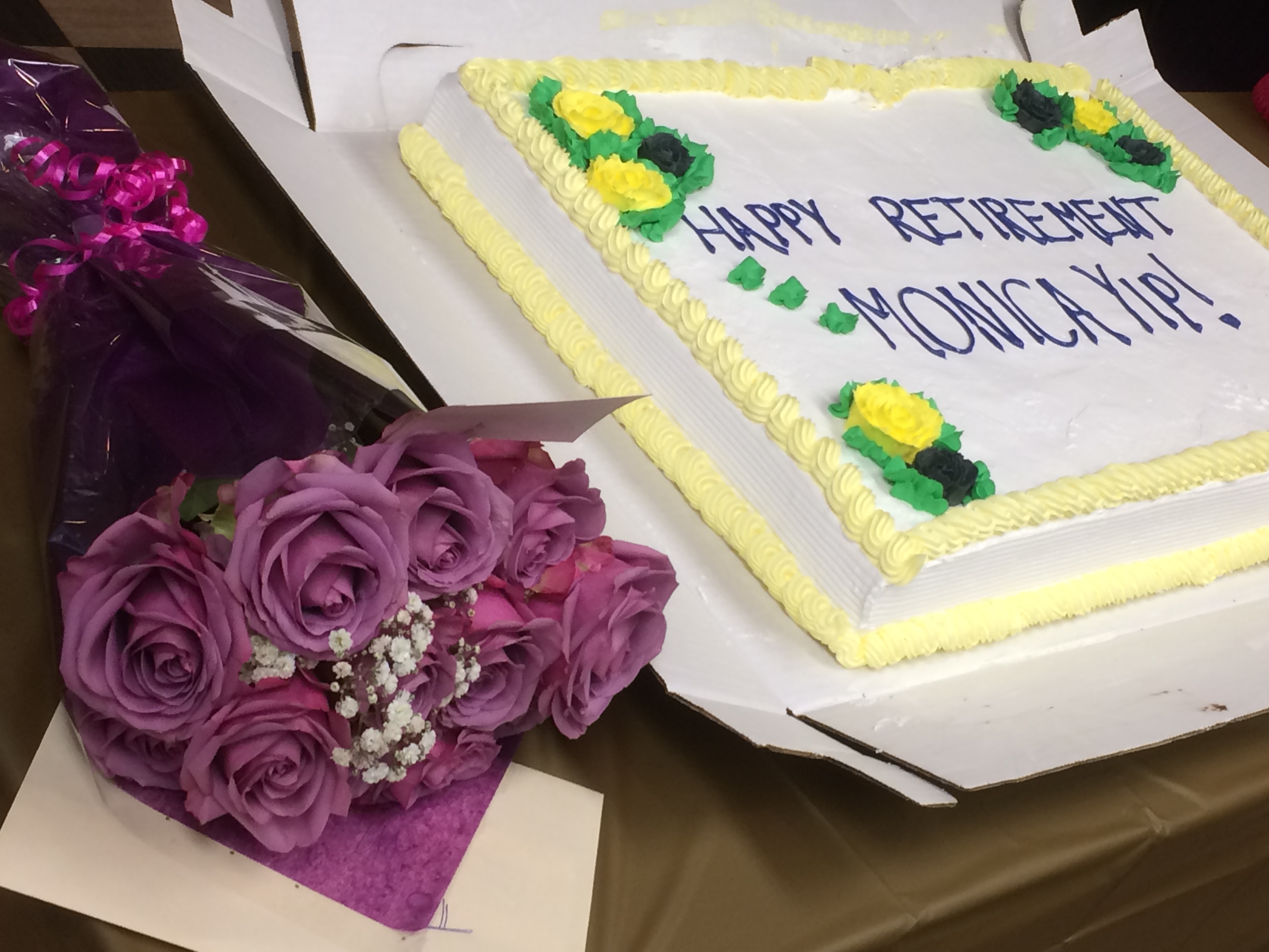 A retirement party cake and bouquet, with the cake reading Happy Retirement Monica Yip.