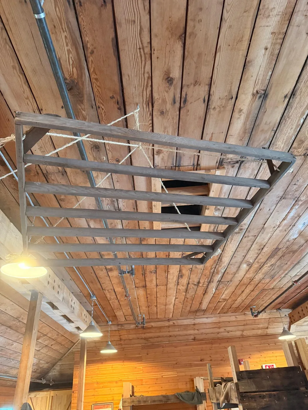 An overhead wooden clothes-drying rack above closely stacked bunks in a historic Steveston workers' dormitory.