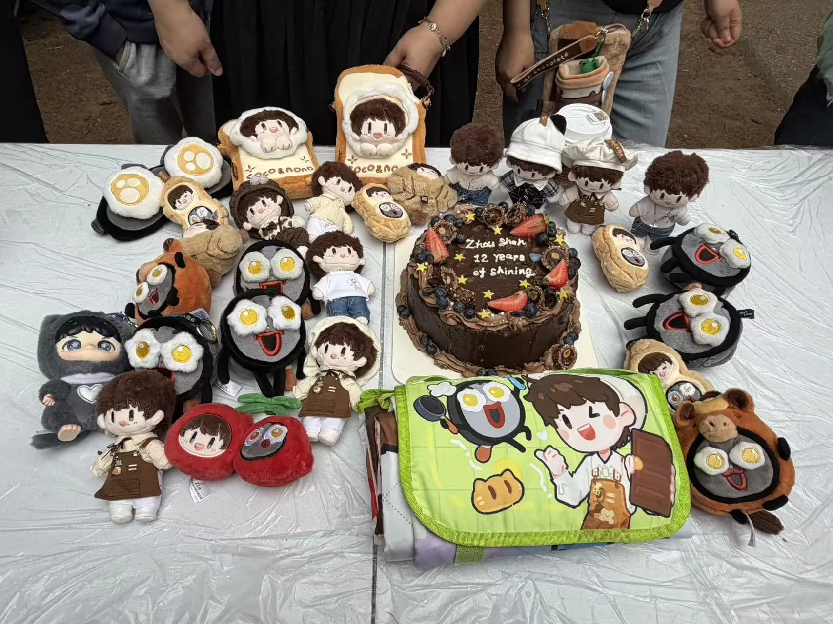 A 12 Years of Shining anniversary cake surrounded by Zhou Shen dolls and fan keepsakes.