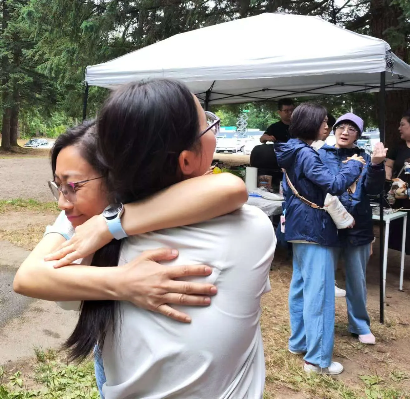 Two community members greeting one another with a warm hug at the picnic.